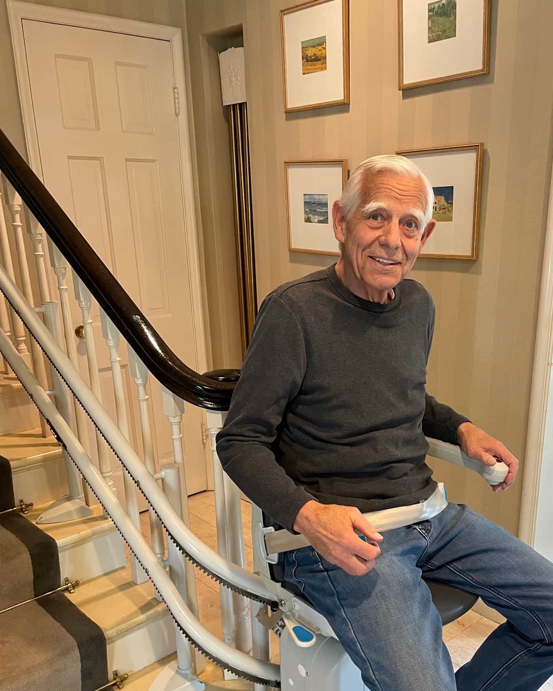 A Safeguard Stairlifts customer seated on a custom curved stairlift in his home
